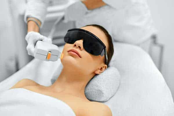 Lying Woman Wearing Safety Googles & Receiving Laser treatment on her Face | Noble Clinic in Draper, UT