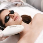 Woman Lying on Medical Cot & Receiving Laser Photo Facial Treatment | Noble Clinic in Draper, UT